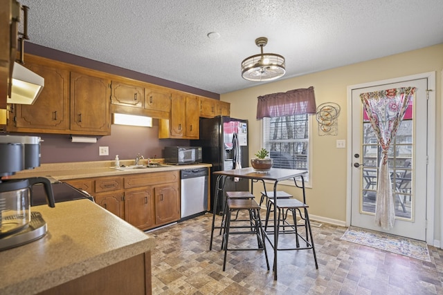 kitchen with stainless steel appliances, extractor fan, sink, and a textured ceiling