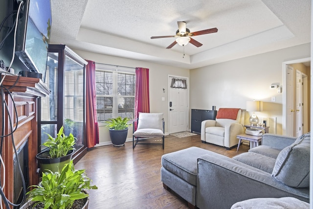 living room featuring ceiling fan, dark hardwood / wood-style floors, a raised ceiling, and a textured ceiling