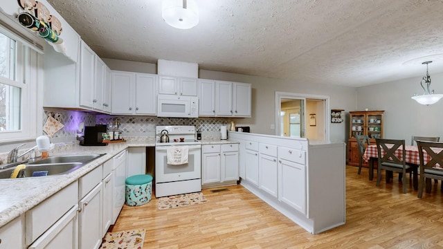 kitchen featuring white cabinetry, sink, white appliances, and decorative light fixtures