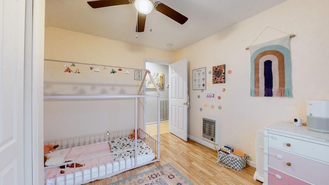 bedroom featuring hardwood / wood-style flooring, ceiling fan, and heating unit