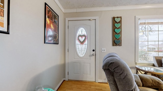 entryway with ornamental molding, a textured ceiling, and light wood-type flooring