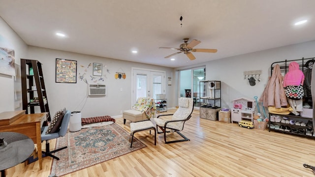 living room with french doors, ceiling fan, a wall mounted AC, and light wood-type flooring