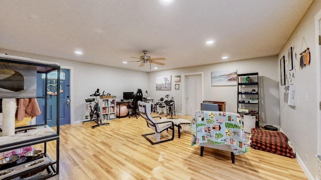 workout room with ceiling fan and light wood-type flooring