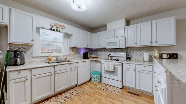 kitchen featuring white cabinetry, white appliances, light hardwood / wood-style floors, and sink