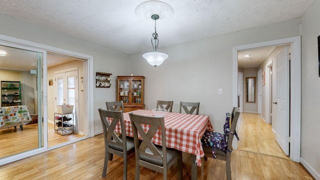 dining space with a textured ceiling and light hardwood / wood-style floors