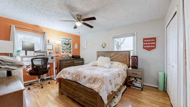 bedroom featuring ceiling fan, light hardwood / wood-style flooring, a closet, and a textured ceiling