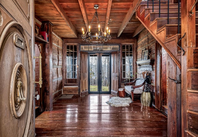 foyer entrance with wooden walls, wood ceiling, dark wood-type flooring, beam ceiling, and french doors