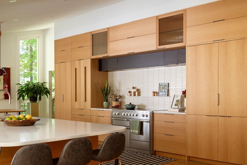 kitchen with tasteful backsplash, double oven range, a kitchen breakfast bar, and light brown cabinets