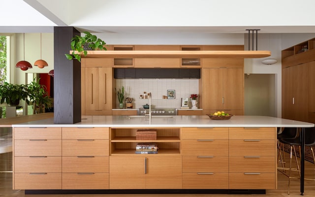 kitchen featuring decorative backsplash, a breakfast bar area, and light brown cabinets