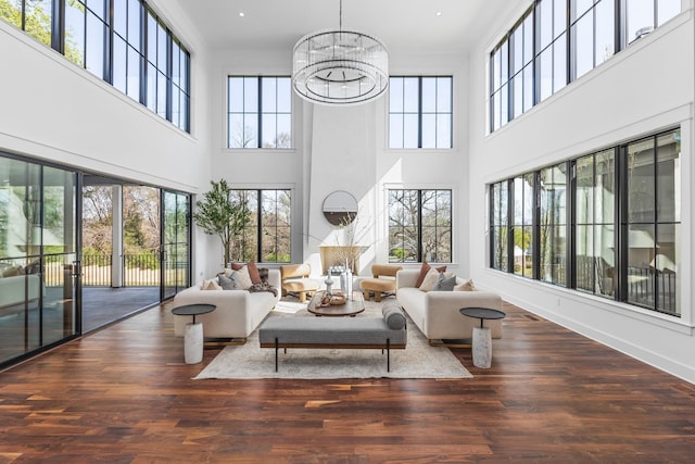 living room with a notable chandelier, a wealth of natural light, and dark wood-type flooring