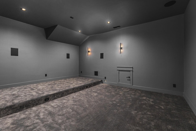 cinema room with vaulted ceiling and dark carpet