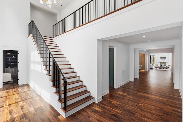 stairs with hardwood / wood-style floors and a high ceiling