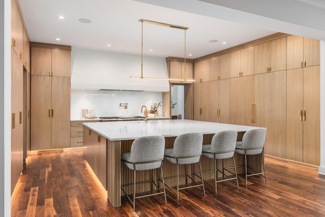 kitchen with a large island, pendant lighting, dark hardwood / wood-style flooring, and light brown cabinets