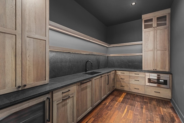 kitchen with light brown cabinetry, tasteful backsplash, sink, dark stone counters, and dark wood-type flooring