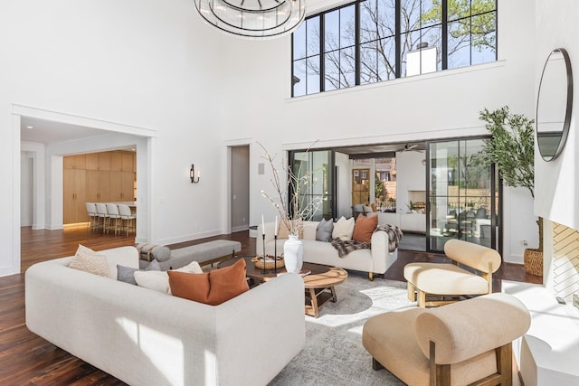 living room with dark hardwood / wood-style floors, an inviting chandelier, and a towering ceiling