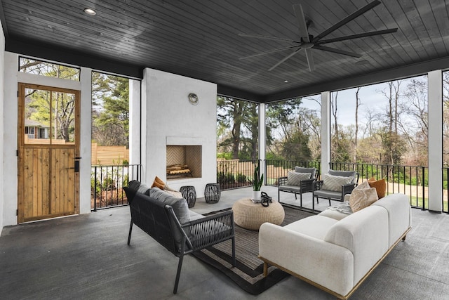 sunroom / solarium with ceiling fan, plenty of natural light, wooden ceiling, and a fireplace