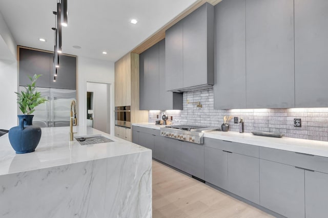 kitchen with appliances with stainless steel finishes, sink, gray cabinetry, backsplash, and hanging light fixtures