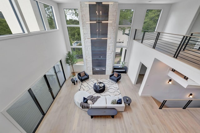 living room featuring a healthy amount of sunlight, a skylight, a high ceiling, and light wood-type flooring