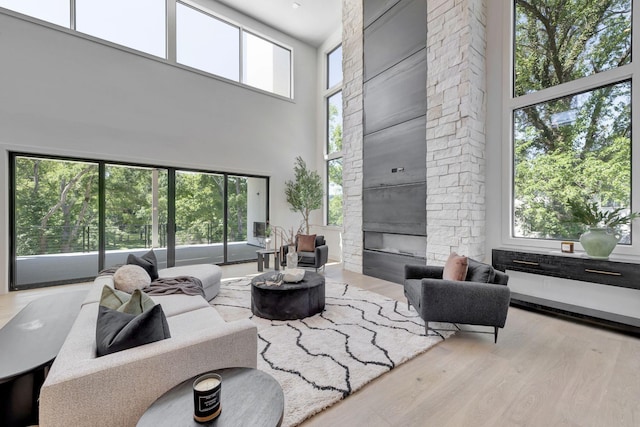 living room featuring a fireplace, a high ceiling, and light wood-type flooring