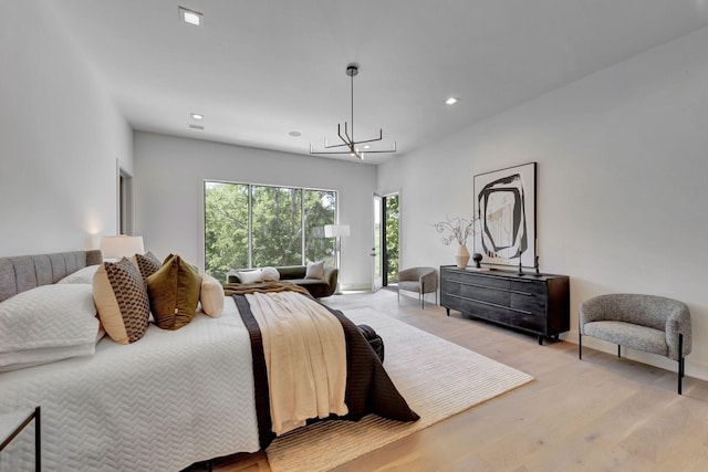 bedroom featuring an inviting chandelier, access to exterior, and light hardwood / wood-style flooring