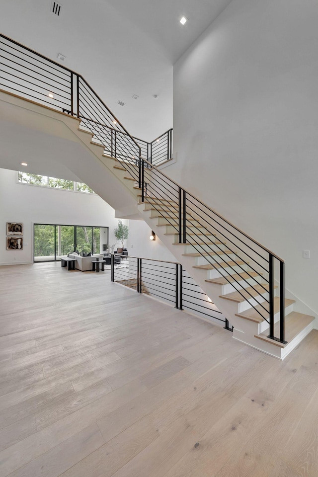 staircase with a towering ceiling and wood-type flooring