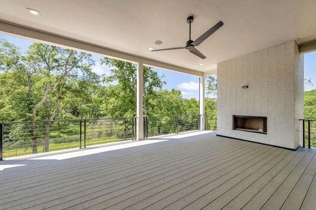 wooden terrace with ceiling fan and a brick fireplace