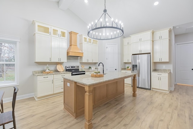 kitchen featuring a kitchen island with sink, premium range hood, white cabinets, and appliances with stainless steel finishes