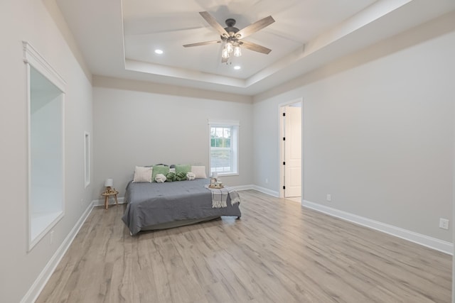 bedroom featuring a tray ceiling, light hardwood / wood-style flooring, and ceiling fan