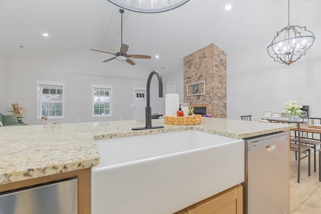 kitchen featuring a stone fireplace, decorative light fixtures, lofted ceiling with beams, sink, and stainless steel dishwasher