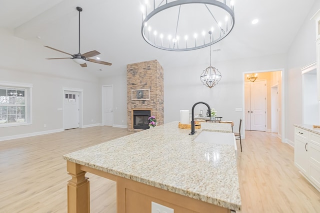 kitchen featuring light stone counters, white cabinets, sink, and pendant lighting