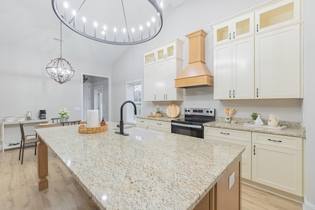 kitchen featuring custom exhaust hood, stainless steel electric range oven, light stone countertops, and a center island with sink