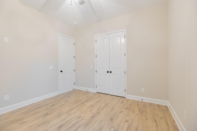 unfurnished bedroom featuring ceiling fan, a closet, and light wood-type flooring