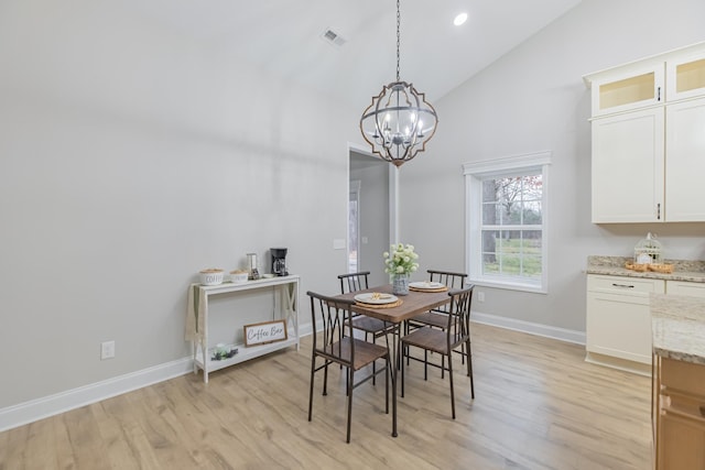 dining area with high vaulted ceiling, a chandelier, and light wood-type flooring