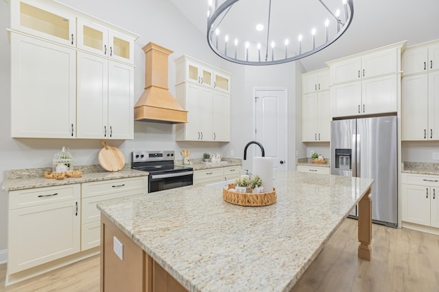 kitchen with appliances with stainless steel finishes, a kitchen island with sink, white cabinets, and custom range hood