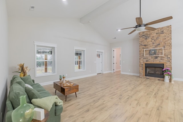 living room featuring ceiling fan, beam ceiling, high vaulted ceiling, a stone fireplace, and light wood-type flooring