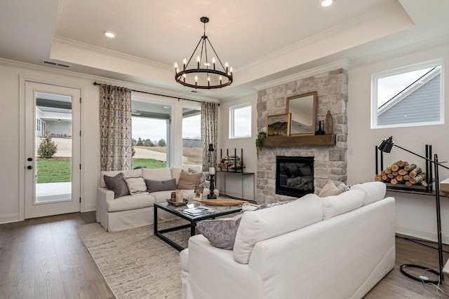 living room featuring hardwood / wood-style floors, a fireplace, ornamental molding, and a raised ceiling