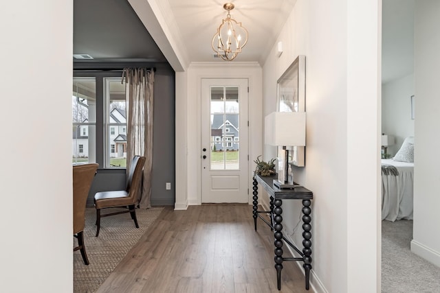 foyer entrance with ornamental molding, a notable chandelier, and light hardwood / wood-style floors