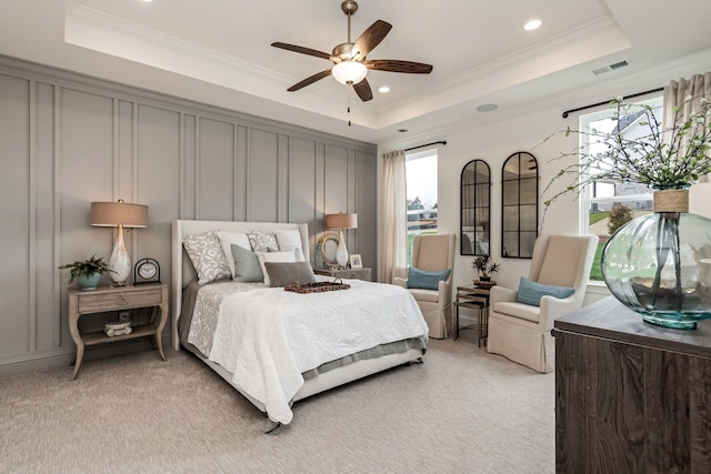 carpeted bedroom featuring ceiling fan, ornamental molding, and a raised ceiling