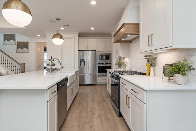 kitchen featuring hanging light fixtures, stainless steel appliances, custom range hood, and white cabinets