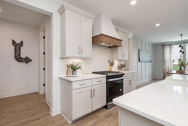 kitchen with white cabinetry, gas stove, premium range hood, and decorative light fixtures