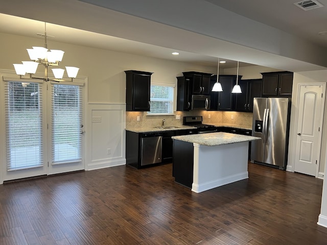 kitchen with stainless steel appliances, light stone countertops, pendant lighting, and dark hardwood / wood-style flooring