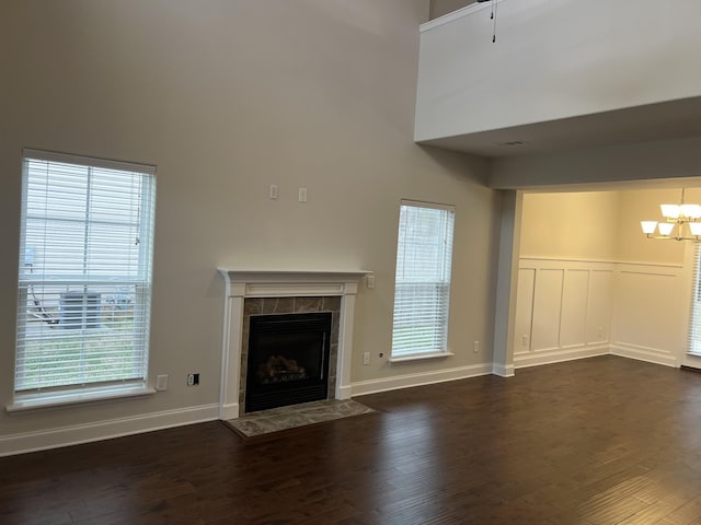 unfurnished living room with dark wood-type flooring, a tile fireplace, and a high ceiling