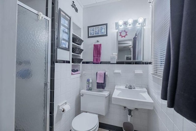 bathroom with sink, crown molding, tile walls, a shower with shower door, and toilet