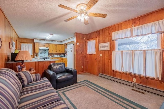 living room featuring light carpet, a baseboard heating unit, wooden walls, and a textured ceiling