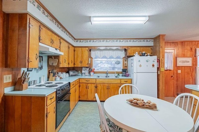 kitchen featuring sink, a textured ceiling, wooden walls, white fridge, and range with electric cooktop