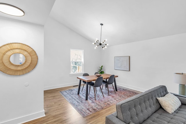 dining area with lofted ceiling, hardwood / wood-style floors, and a notable chandelier