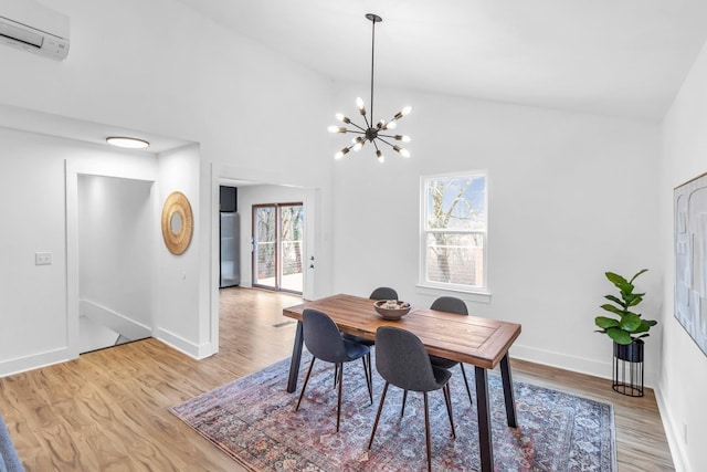 dining area with high vaulted ceiling, light hardwood / wood-style floors, a chandelier, and a wall mounted AC