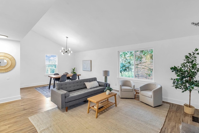 living room featuring an inviting chandelier, vaulted ceiling, and light hardwood / wood-style flooring