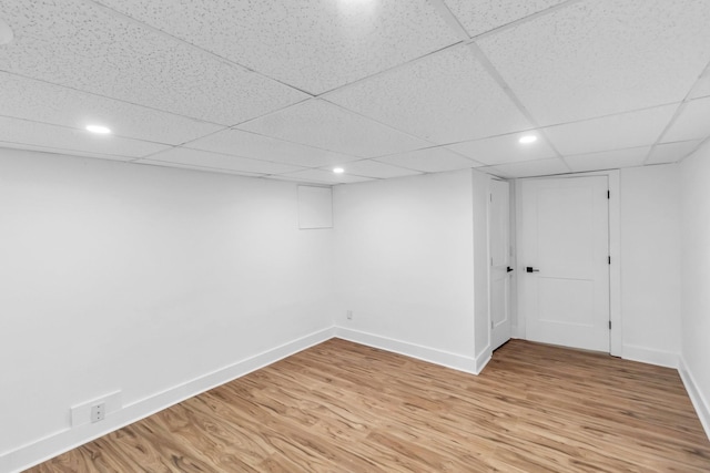 basement with a paneled ceiling and light hardwood / wood-style floors