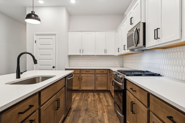 kitchen featuring sink, tasteful backsplash, hanging light fixtures, stainless steel appliances, and white cabinets